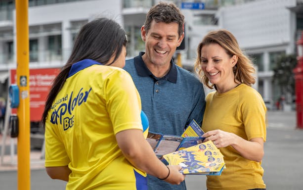 Auckland Explorer Bus staff assisting tourists with brochures.