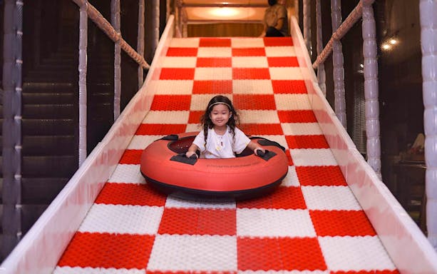 Child sliding on a red and white checkered slide at Jungle Gym, Kuala Lumpur.