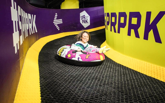 Girl sliding on colorful air tube at SuperPark, Malaysia indoor playground.