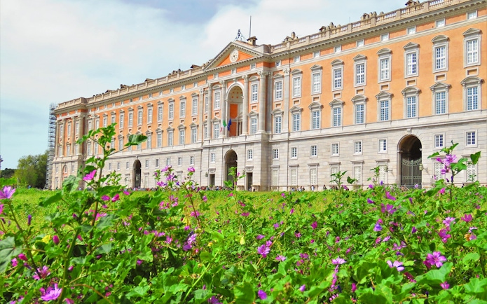 Royal Palace of Caserta facade with blooming flowers in foreground, Caserta, Italy.