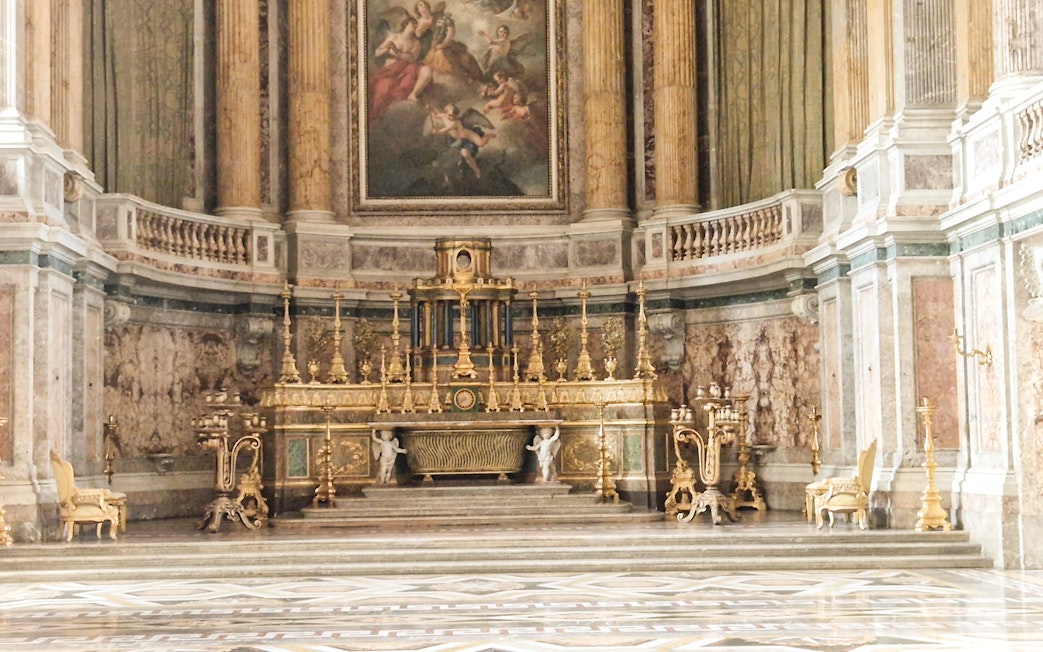 Royal Palace of Caserta ornate interior with gilded altar and marble columns.