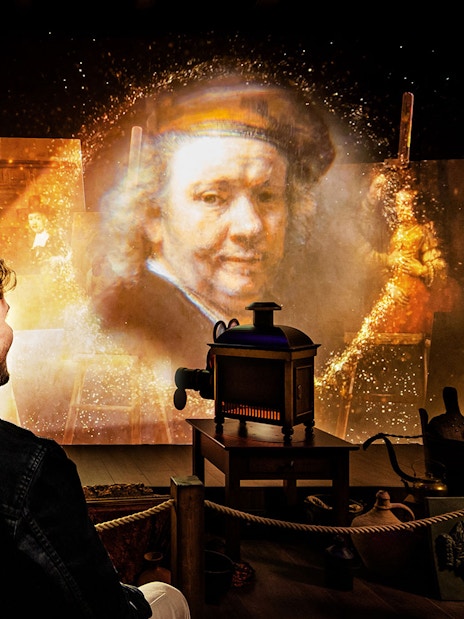 Couple enjoying Rembrandts Amsterdam Experience with projected artwork and historical ambiance.