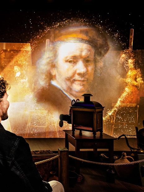 Couple enjoying Rembrandts Amsterdam Experience with projected artwork and historical ambiance.