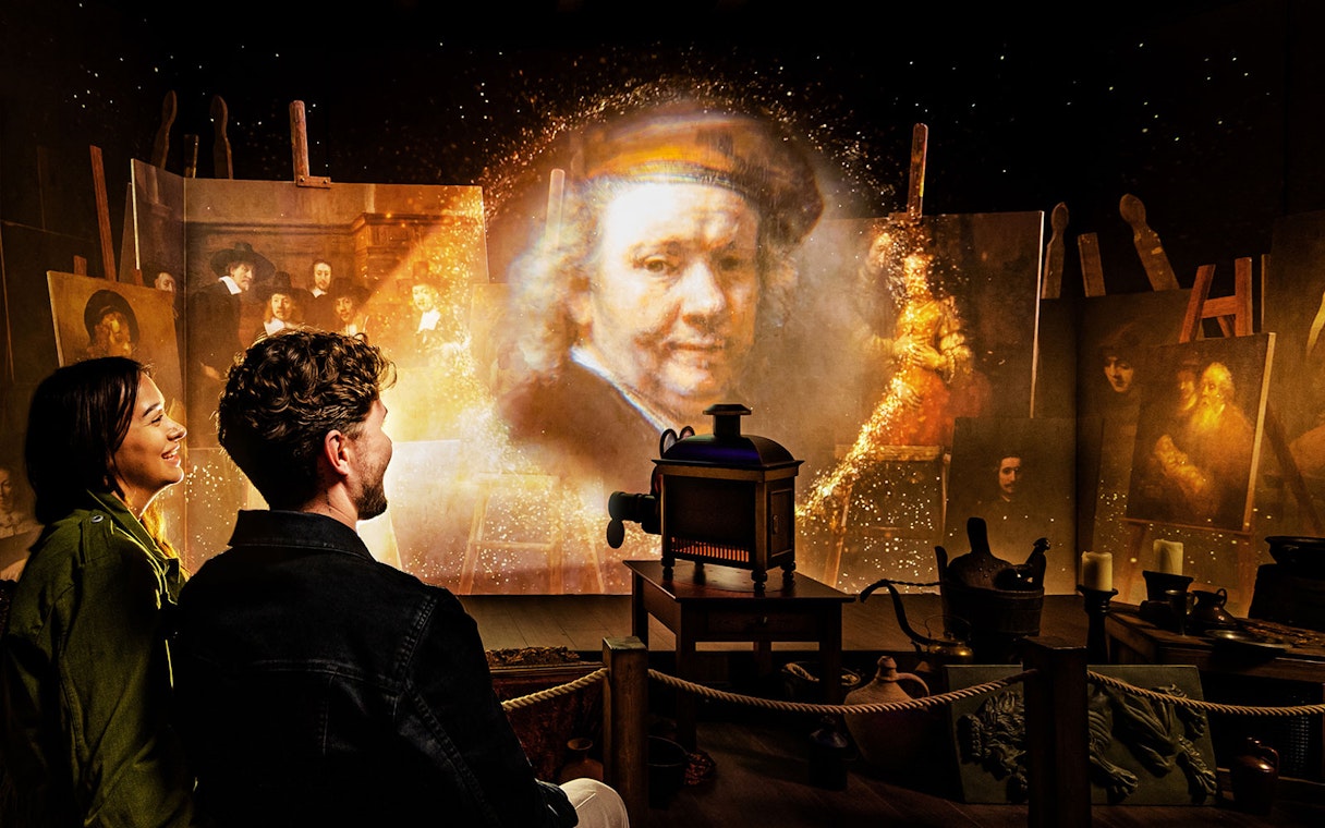 Couple enjoying Rembrandts Amsterdam Experience with projected artwork and historical ambiance.