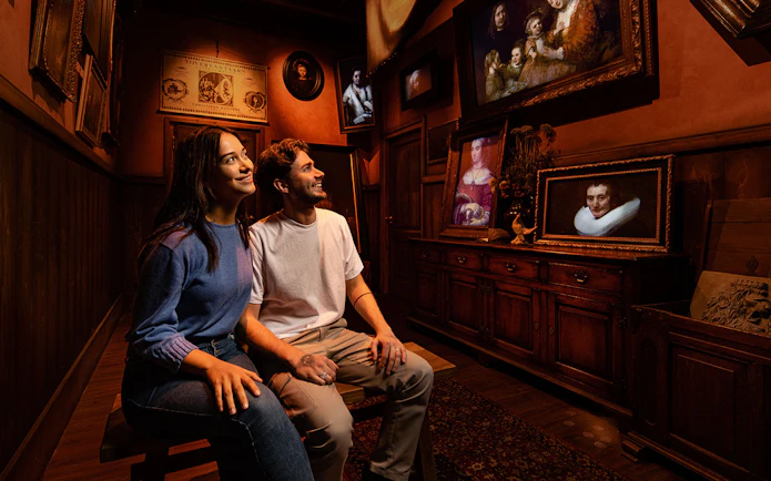 Tourists enjoying Rembrandt's Amsterdam Experience surrounded by classic paintings.