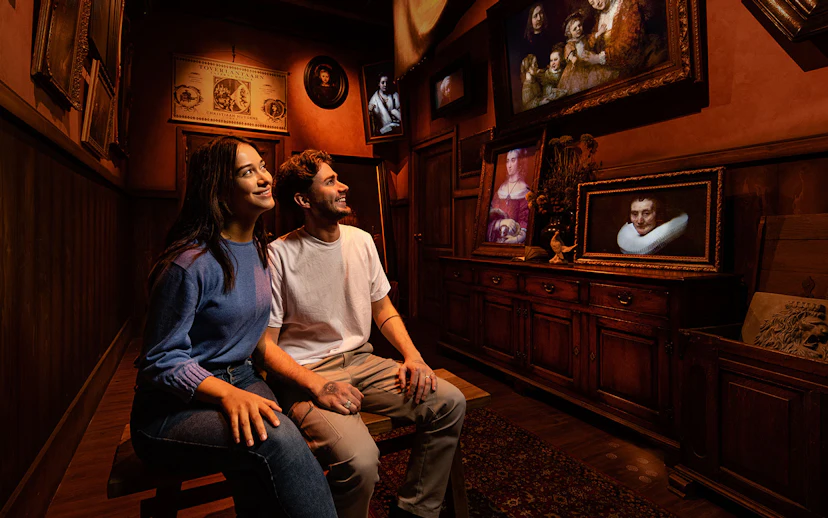 Tourists enjoying Rembrandt's Amsterdam Experience surrounded by classic paintings.