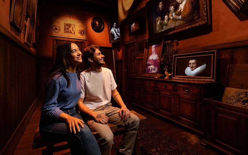 Tourists enjoying Rembrandt's Amsterdam Experience surrounded by classic paintings.