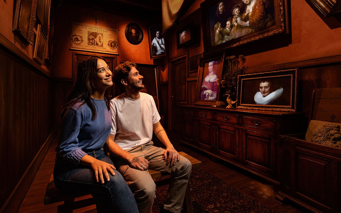 Tourists enjoying Rembrandt's Amsterdam Experience surrounded by classic paintings.