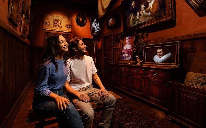 Tourists enjoying Rembrandt's Amsterdam Experience surrounded by classic paintings.