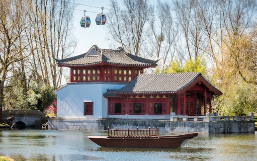 Traditional Chinese pavilion by a pond with cable cars above, Gardens of the World tour.