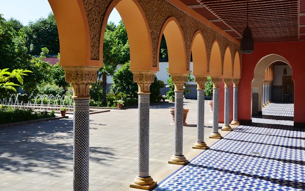 Arched walkway with patterned columns in Gardens of the World tour.