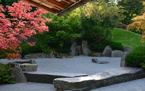 Zen garden with raked gravel, rocks, and vibrant red maple tree in Gardens of the World tour.