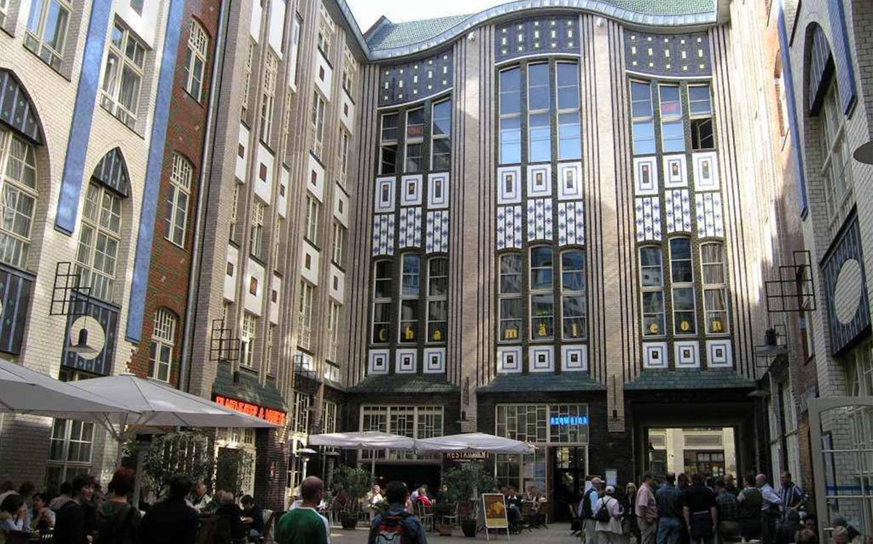 Courtyard of Hackesche Höfe in Berlin with people on a guided tour.