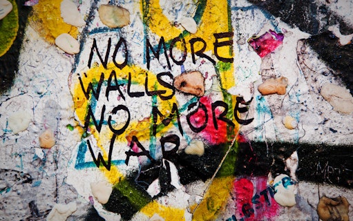 Graffiti on Berlin Wall reading "No more walls, no more war" during guided tour.