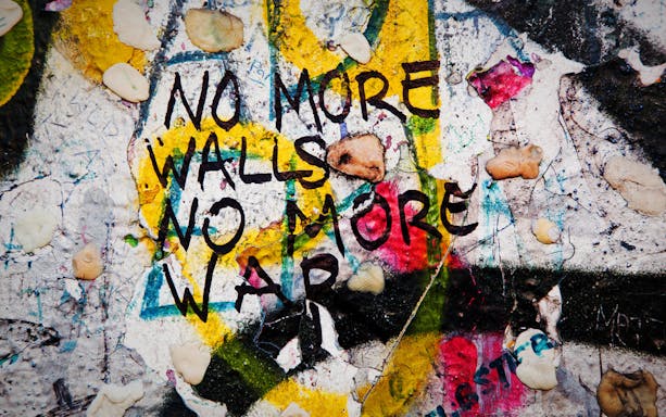 Graffiti on Berlin Wall reading "No more walls, no more war" during guided tour.