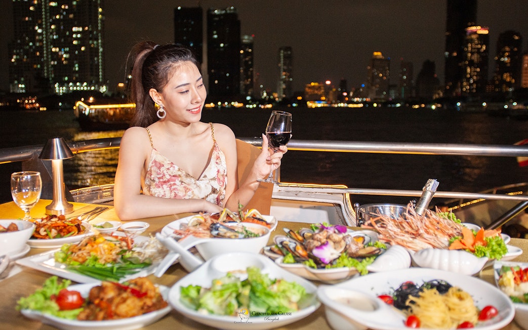 Buffet dinner on Chao Phraya Cruise with city skyline in Bangkok.