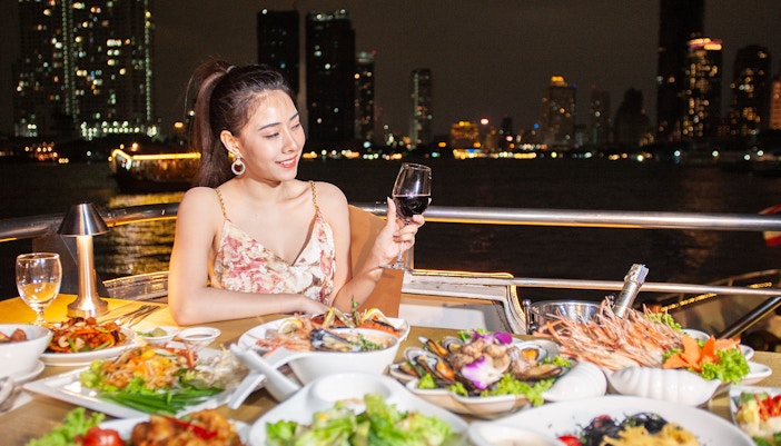Buffet dinner on Chao Phraya Cruise with city skyline in Bangkok.