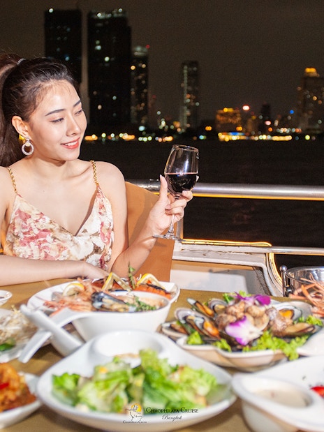Buffet dinner on Chao Phraya Cruise with city skyline in Bangkok.