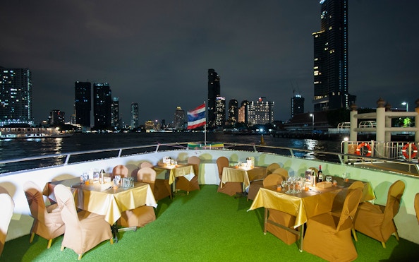 Dining setup on Chao Phraya Cruise with Bangkok skyline at night.