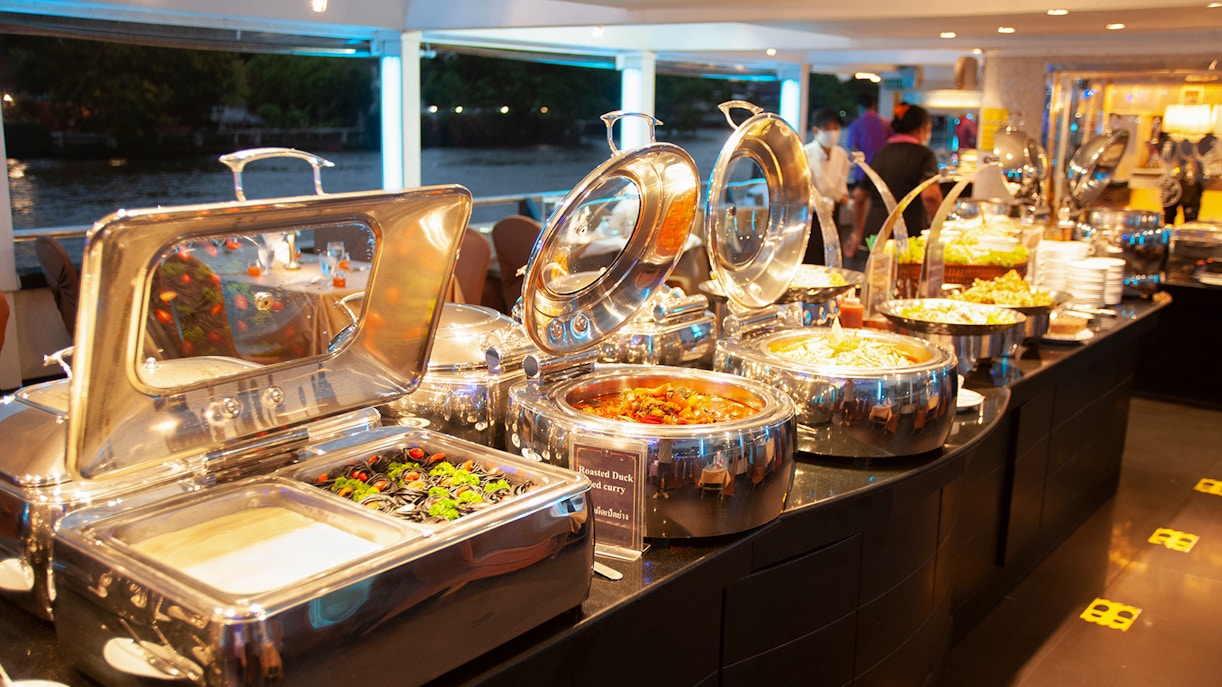 Buffet setup on Chao Phraya Cruise with various dishes and river view.