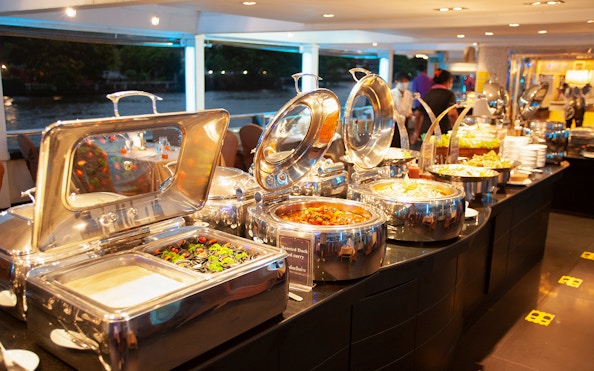 Buffet setup on Chao Phraya Cruise with various dishes and river view.