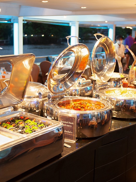 Buffet setup on Chao Phraya Cruise with various dishes and river view.