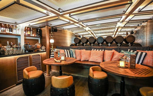 Cozy seating area on Sirimahannop Dinner Cruise at Asiatique The Riverfront with bar and lanterns.
