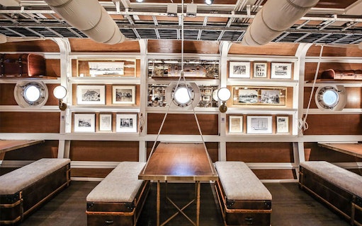 Interior of Sirimahannop Dinner Cruise at Asiatique The Riverfront, featuring nautical decor and framed photos.