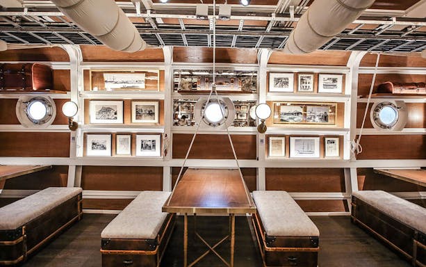 Interior of Sirimahannop Dinner Cruise at Asiatique The Riverfront, featuring nautical decor and framed photos.