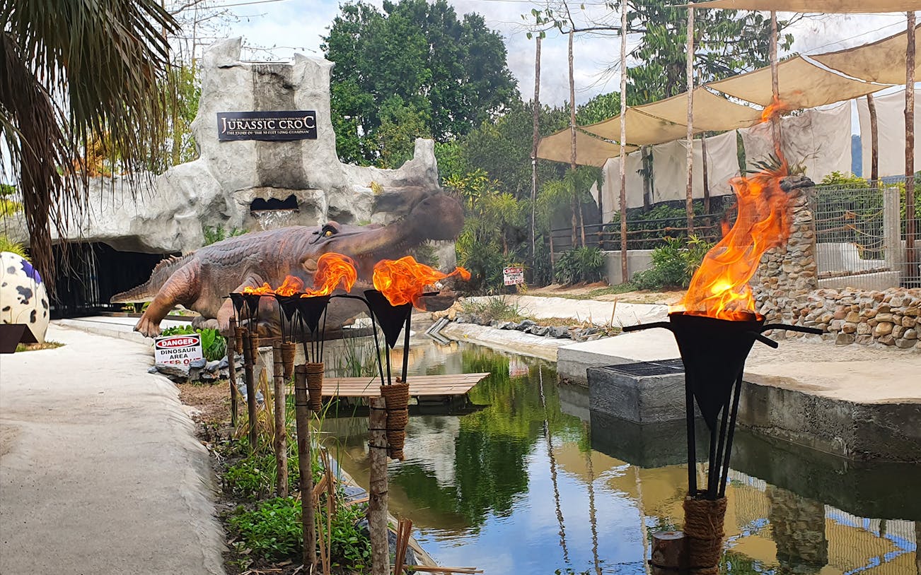 Crocodile Adventureland Langkawi entrance with dinosaur statue and flaming torches.