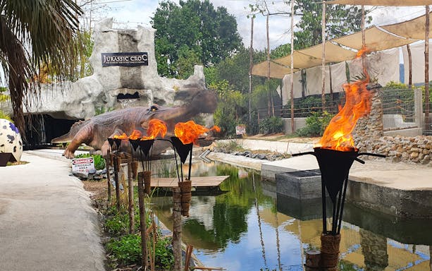 Crocodile Adventureland Langkawi entrance with flaming torches and dinosaur sculpture.