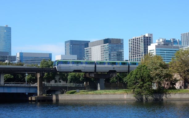 Monorail traveling from Haneda Airport to Tokyo with city skyline in background.