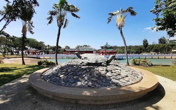 Turtle statue at Kusu Island with traditional pavilions and palm trees in Singapore.