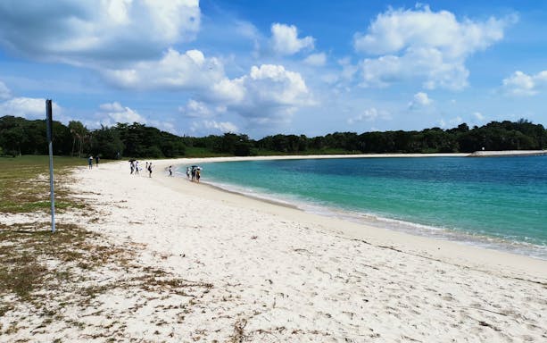 Tourists walking along the sandy beach of Lazarus Island, Singapore.