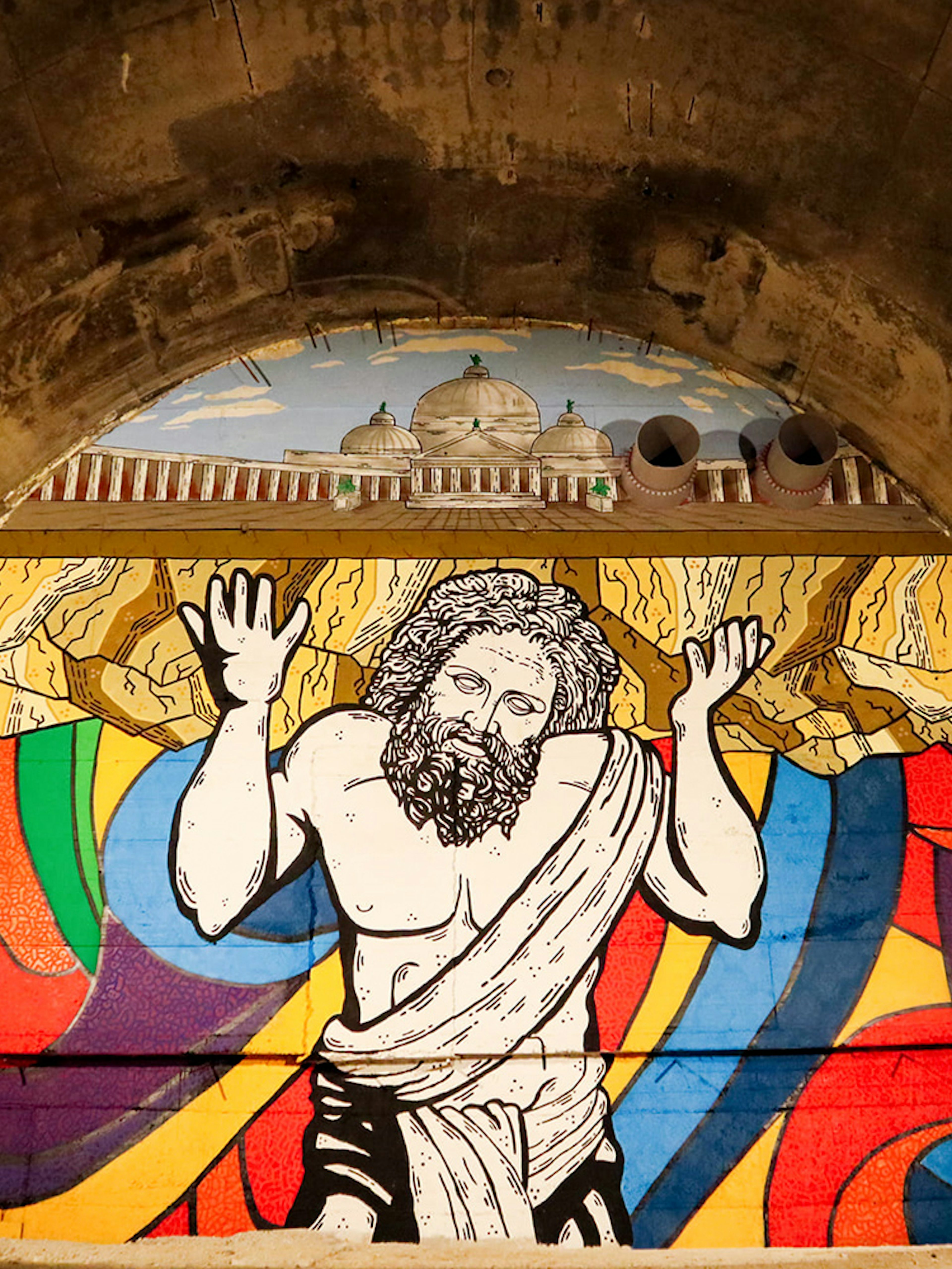 Mural of Atlas in Bourbon Tunnel, Naples, with colorful abstract background.