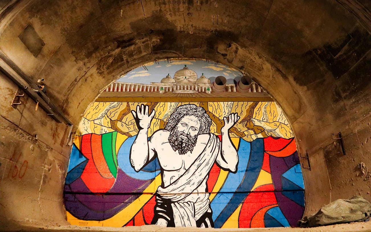 Mural of Atlas in Bourbon Tunnel, Naples, with colorful abstract background.