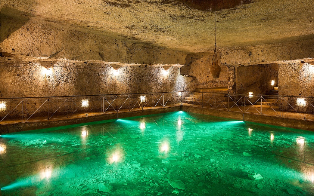 Bourbon Tunnel guided tour showing illuminated underground pool and stone walls.