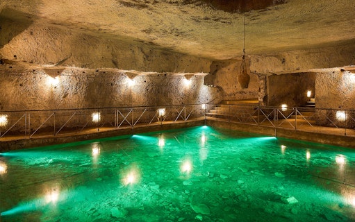Bourbon Tunnel guided tour showing illuminated underground pool and stone walls.