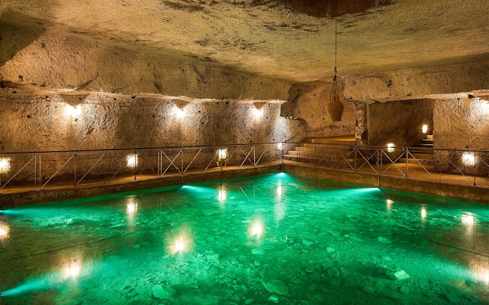 Bourbon Tunnel guided tour showing illuminated underground pool and stone walls.