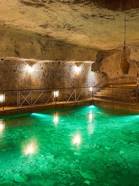 Bourbon Tunnel guided tour showing illuminated underground pool and stone walls.
