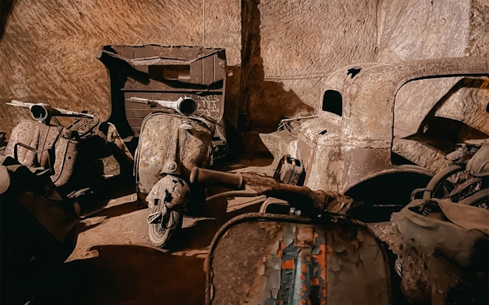 Vintage scooters and car remnants in Bourbon Tunnel, Naples.