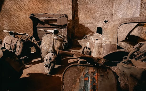 Vintage scooters and car remnants in Bourbon Tunnel, Naples.