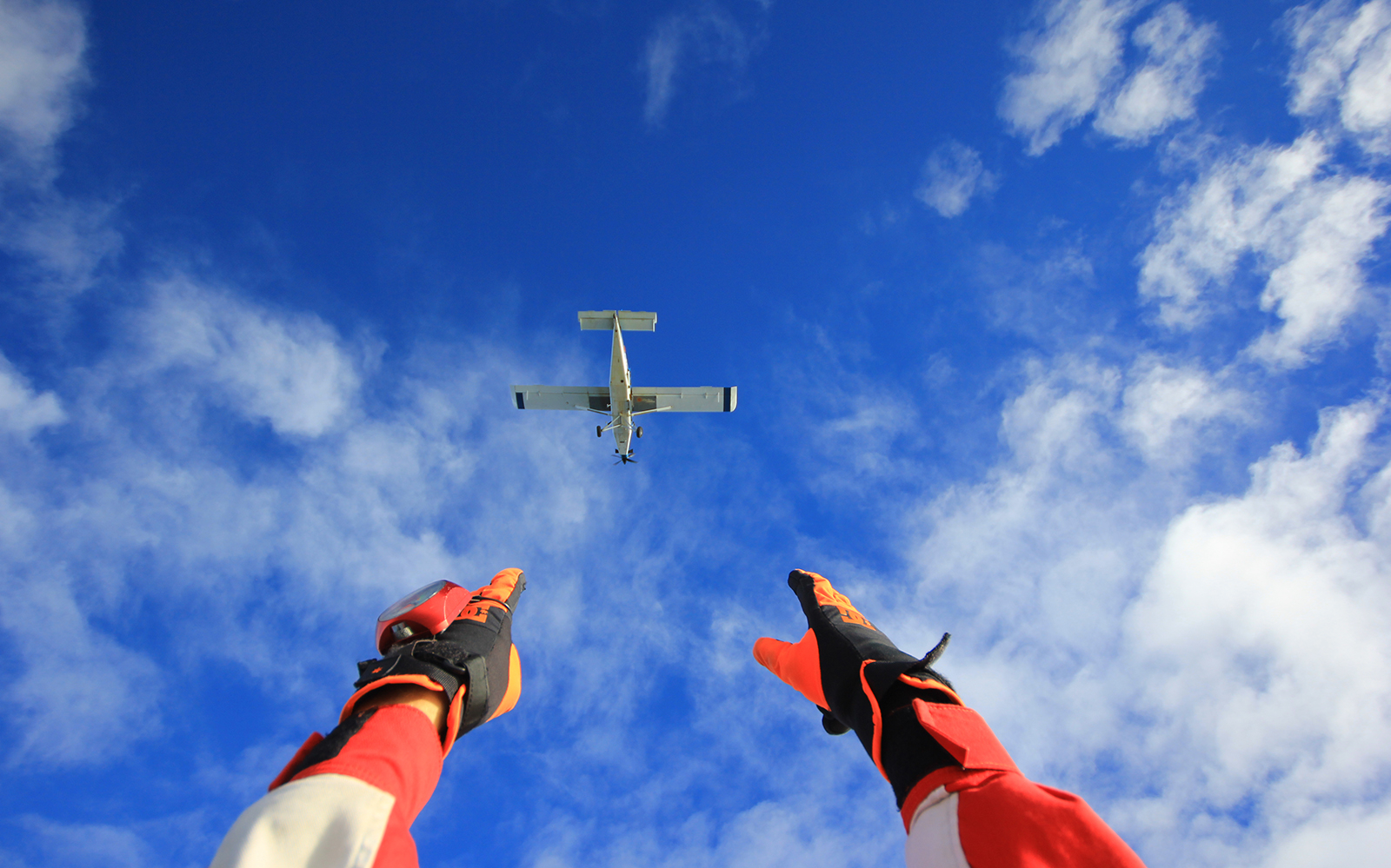 Skydiver reaching towards plane in Abel Tasman skydive experience.