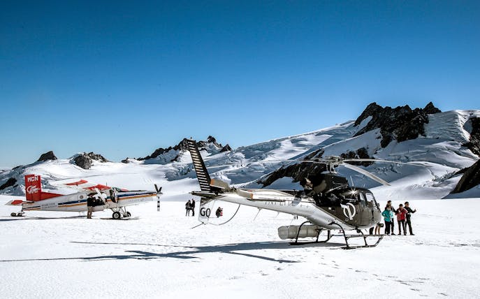 Skiplane and helicopter on snowy alpine landscape with tourists, Ultimate Alpine Experience.