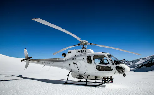 Helicopter on snowy landscape during 35-minute Tasman Experience flight.