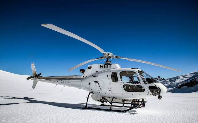 Helicopter on snowy landscape during 35-minute Tasman Experience flight.