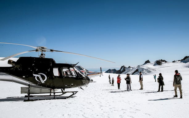 Helicopter on snowy glacier with tourists during 45-minute flight tour.