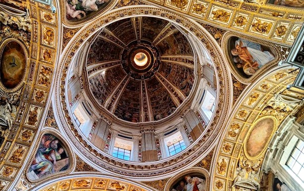 Interior dome of Santa Maria Maggiore Basilica with detailed frescoes and ornate gold accents.