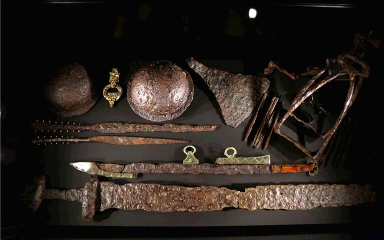 Viking artifacts including swords, helmets, and tools displayed at The Vikings Exhibition.