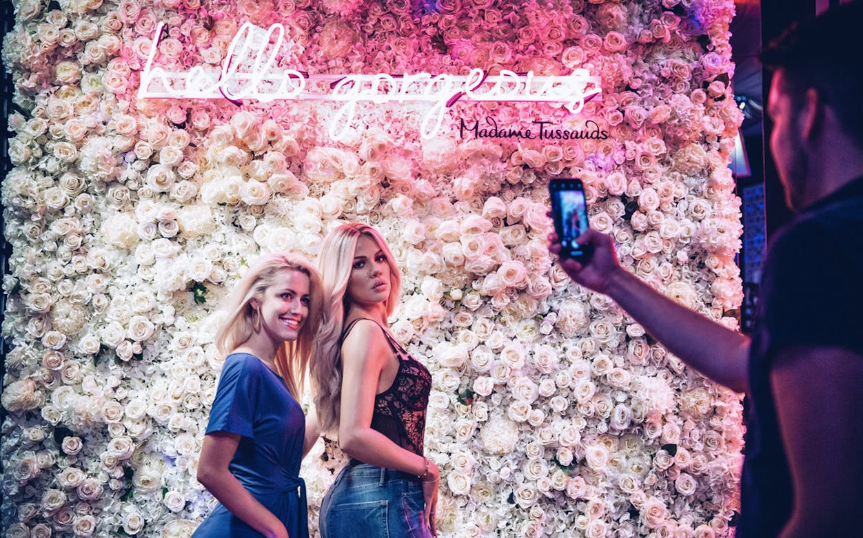 Visitors posing at Madame Tussauds Las Vegas with floral backdrop.